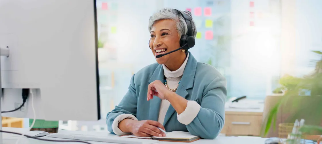 Adobestock 650170201 ©Wesley Jvr Peopleimages.Com WEB Eine mittelalte Frau mit Headset schaut auf einen Computer-Bildschirm