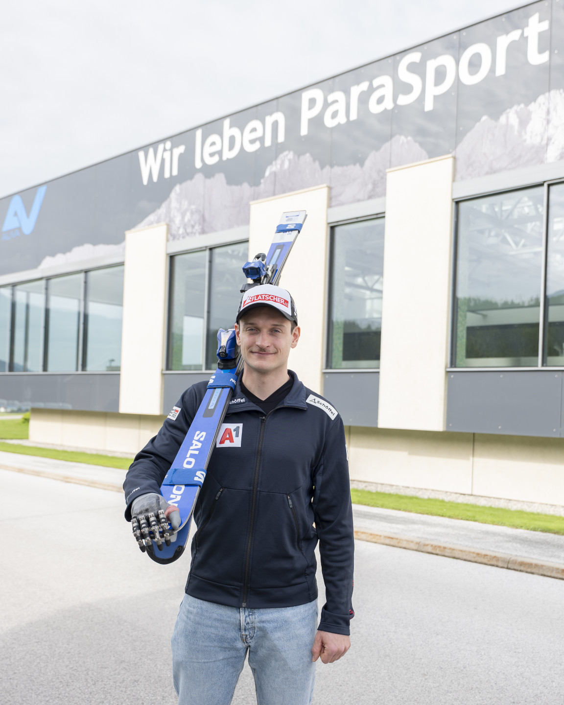 Paraskifahrer Thomas Volgger steht mit seinen Ski vor dem Parasportzentrum, im Hintergrund sieht man den Schriftzug "Wir leben ParaSport" am Gebäude