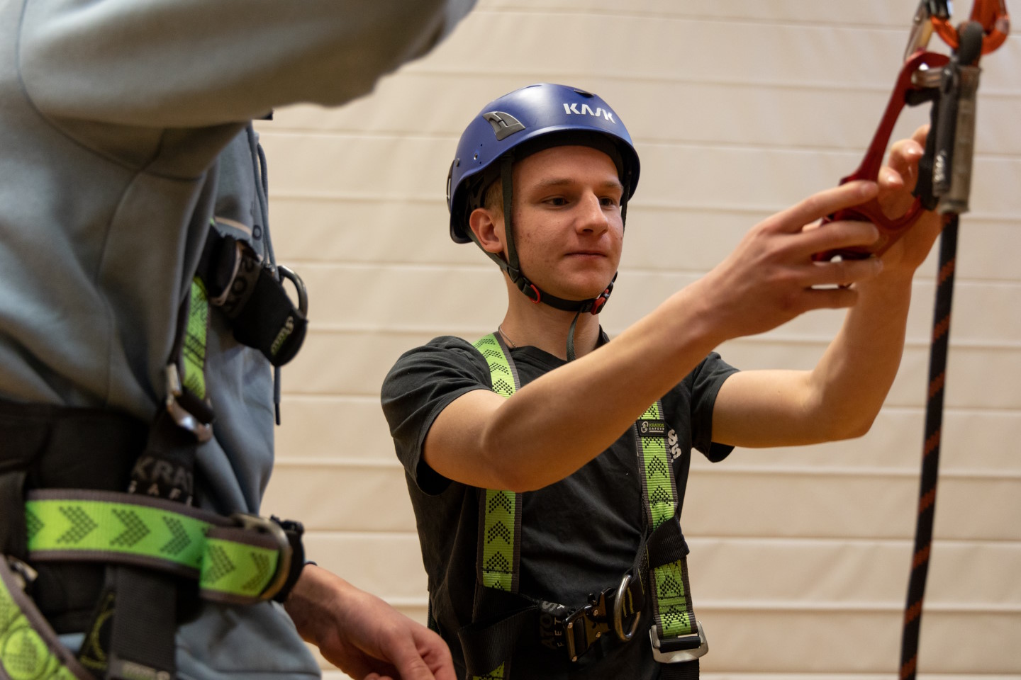 Junger Mann mit Helm, Kletterseil und Karabiner
