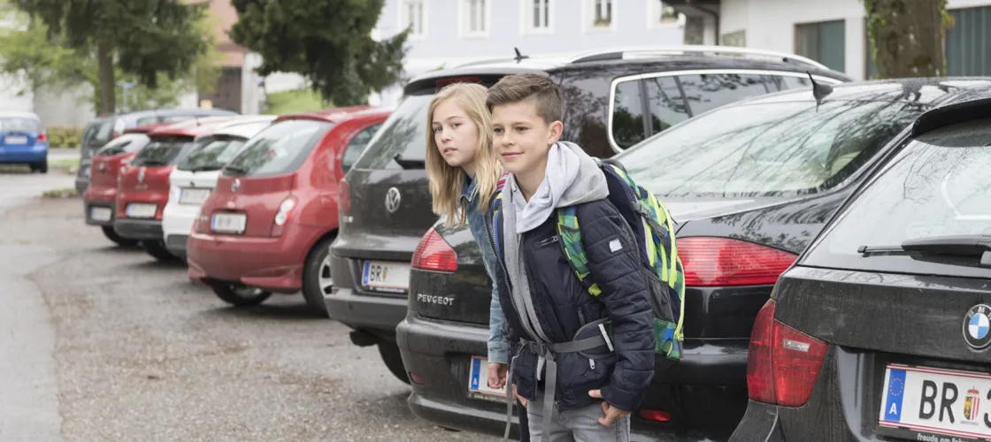 R.Reichhart Foto 1440 Blog 1 Zwei Kinder schauen zwischen parkenden Autos auf die Straße