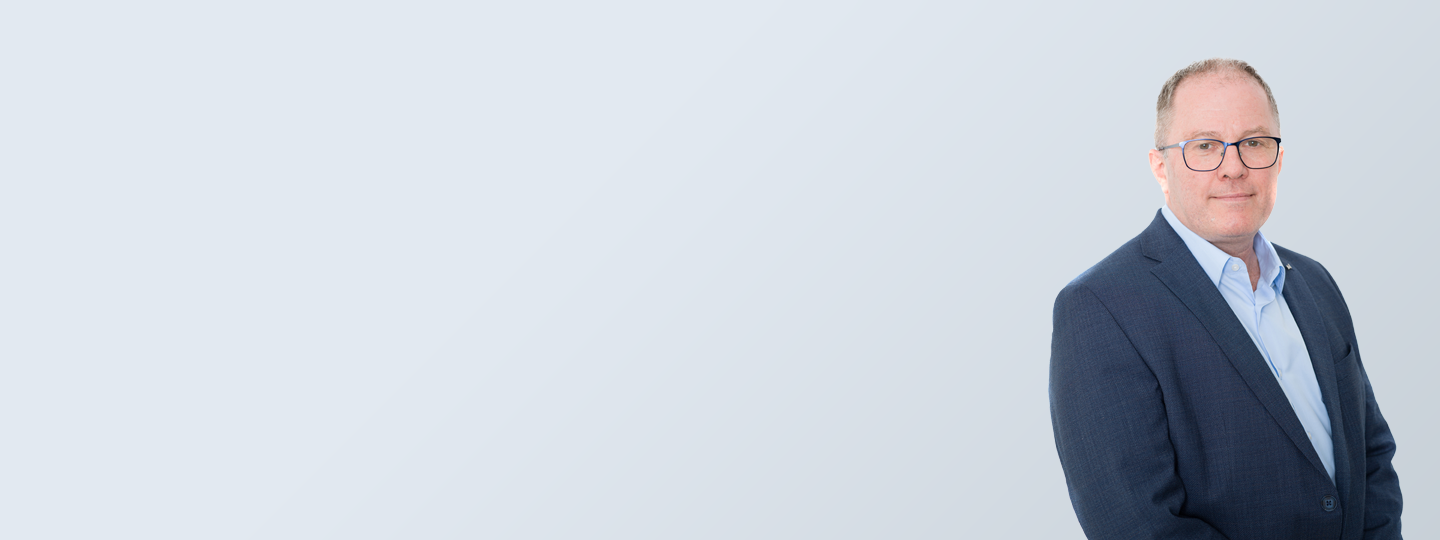 Porträtbild mit grauem Hintergrund von Dr. Thomas Hausner