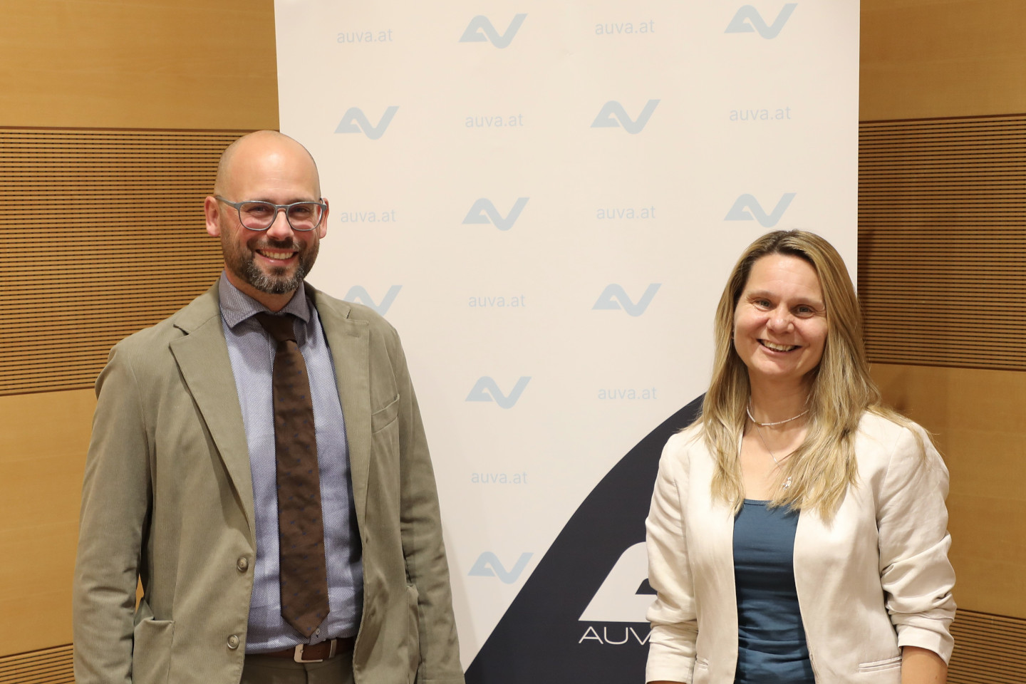 Georg Mattiassich und Stephanie Niederhuber stehen vor einem Banner der AUVA