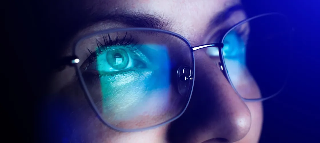 517016413 1440 Credit Vadym Stock.Adobe.Com Nahaufnahme eines Frauengesichts mit Brille, in der sich ein Bildschirm spiegelt.