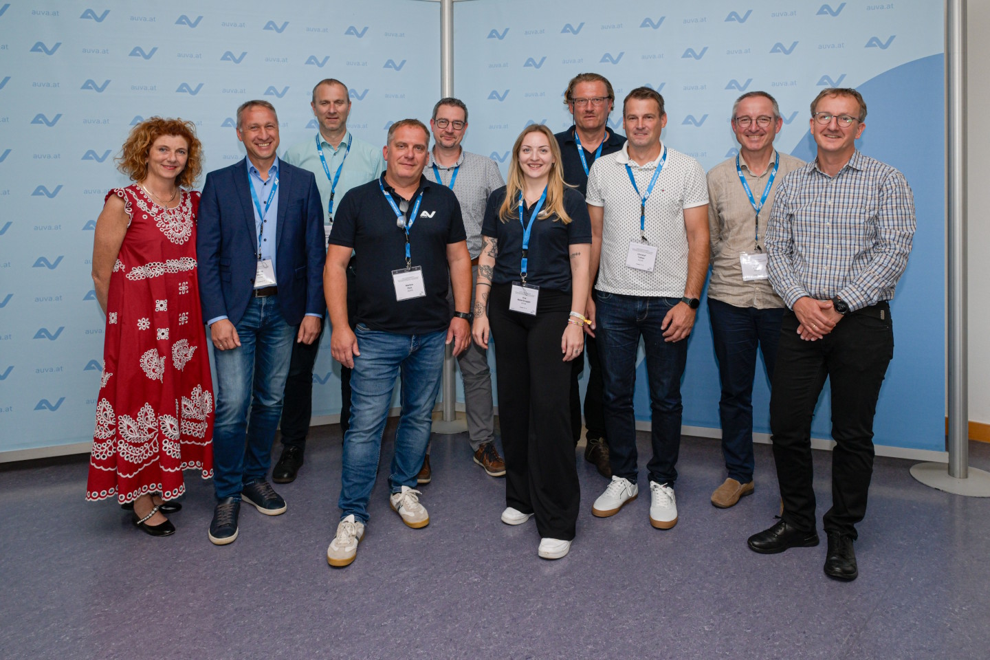 Eine Gruppe von Erwachsenen steht vor einer AUVA-Logowand