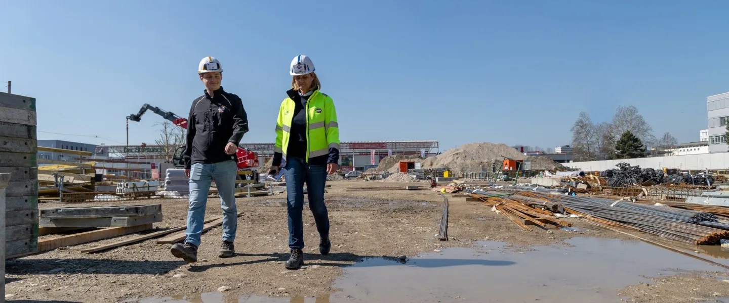 Bau Interview Doppler Edit 1440 1 Credit Kierner Eine Frau und ein Mann gehen auf einer Baustelle