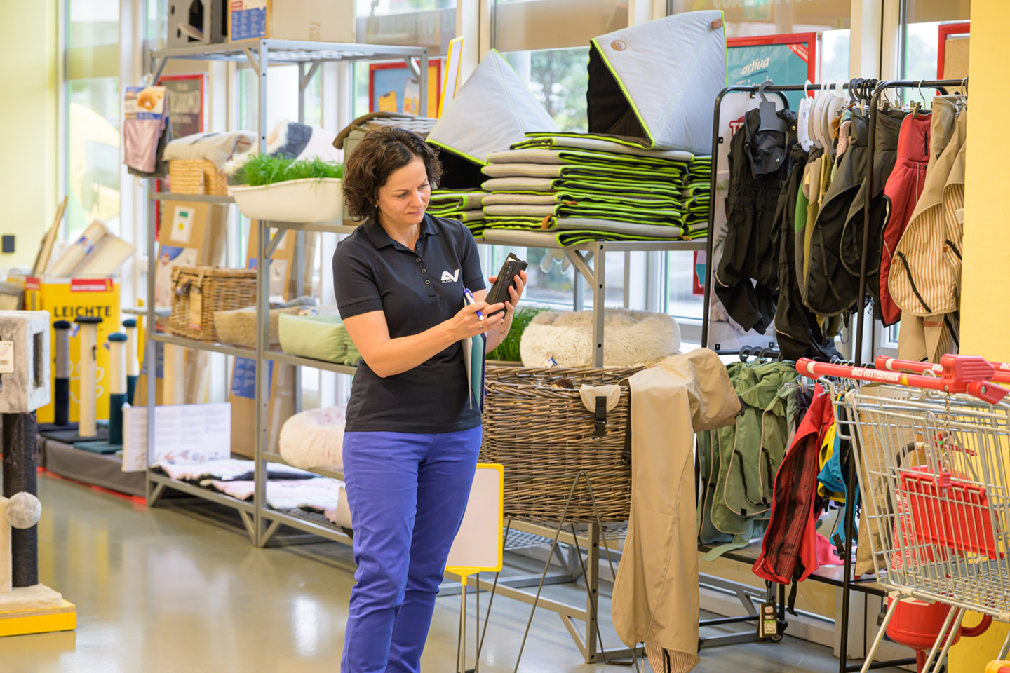 Eine Frau steht in einem Geschäft und fotografiert mit dem Mobiltelefon.