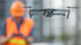 Arbeiter mit Warnweste nutzt Drohne.