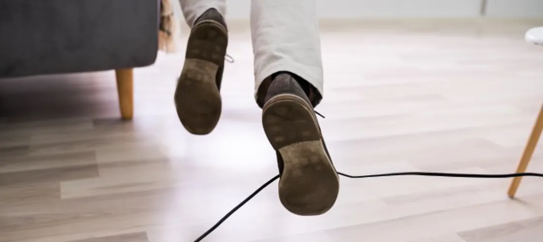 Über ein am Boden liegendes Kabel stürzende Person
