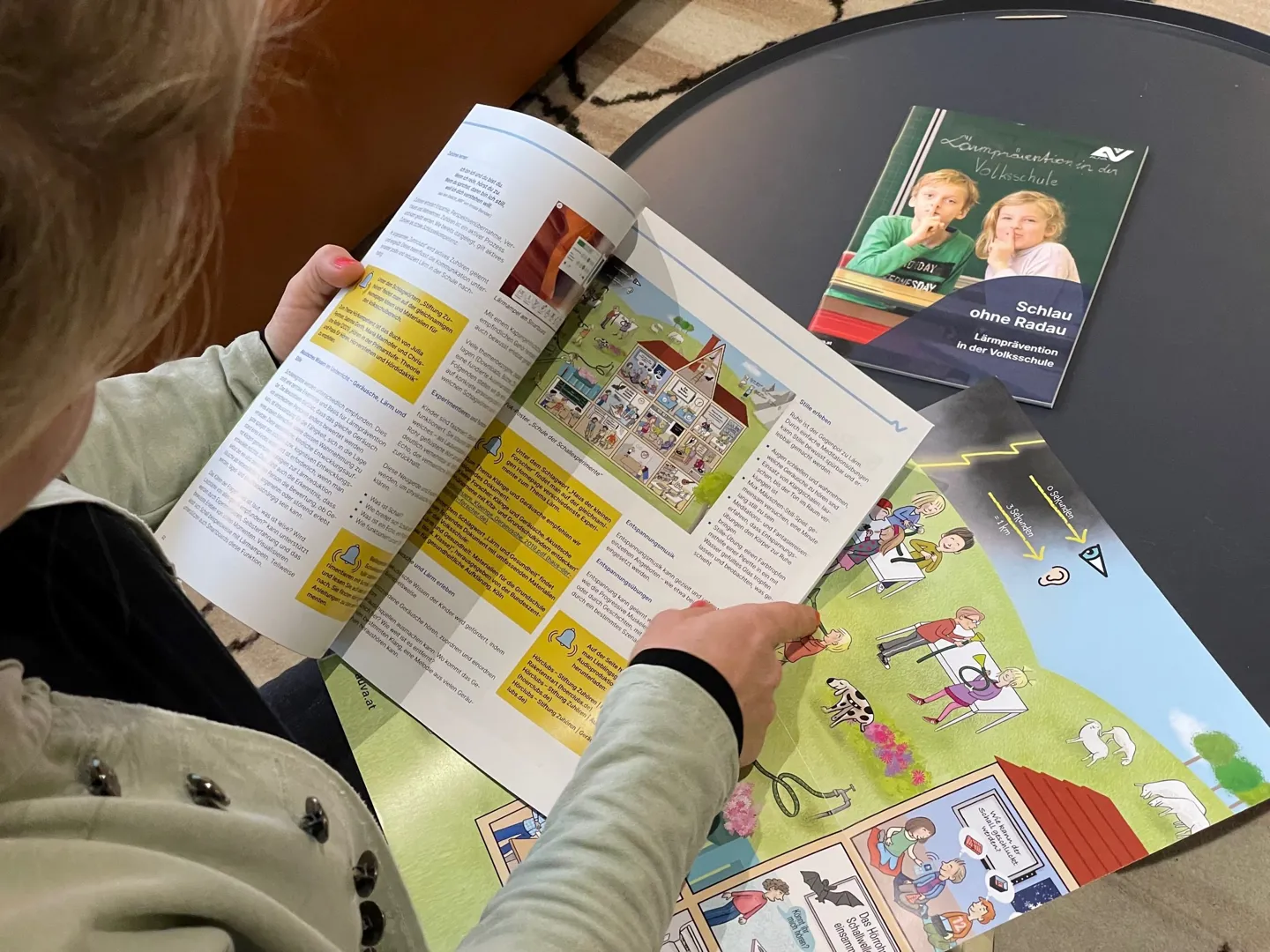Ein Kind betrachtet mehrere aufgeschlagene Magazine, die auf einem Tisch liegen Ein Kind betrachtet mehrere aufgeschlagene Magazine, die auf einem Tisch liegen
