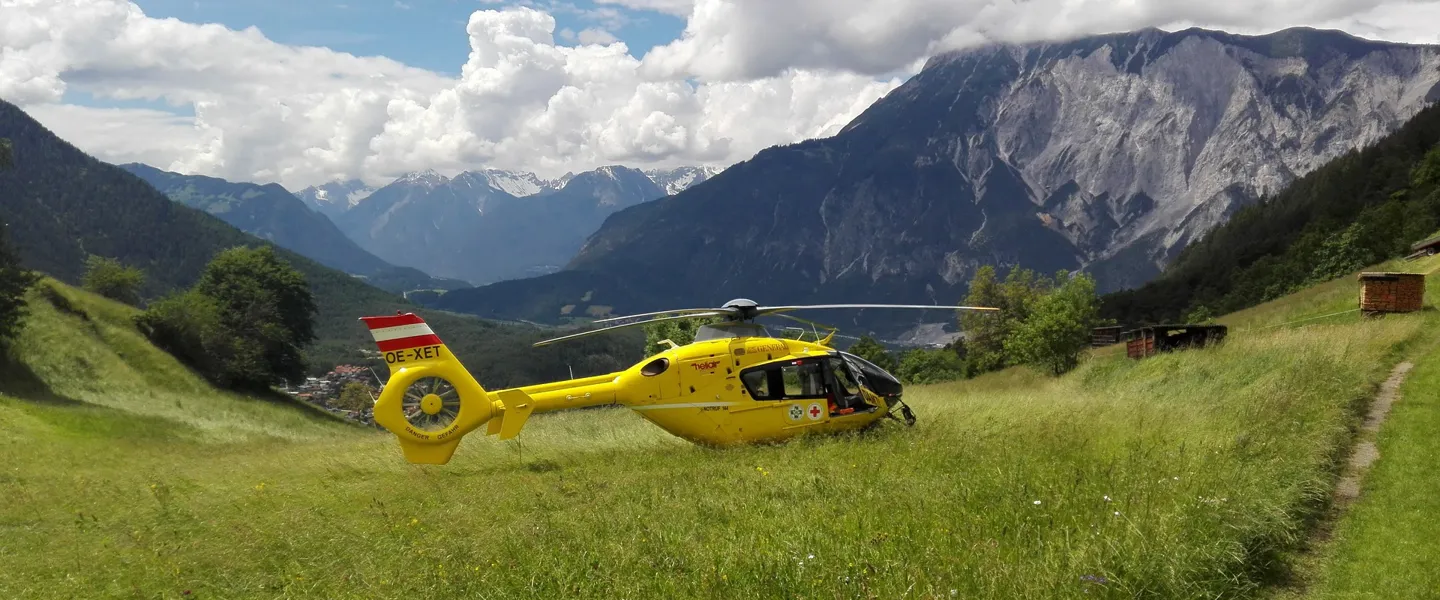 Ein gelber Rettungshubschrauber ist auf einer grünen Wiese in den Bergen gelandet. Ein gelber Rettungshubschrauber ist auf einer grünen Wiese in den Bergen gelandet.