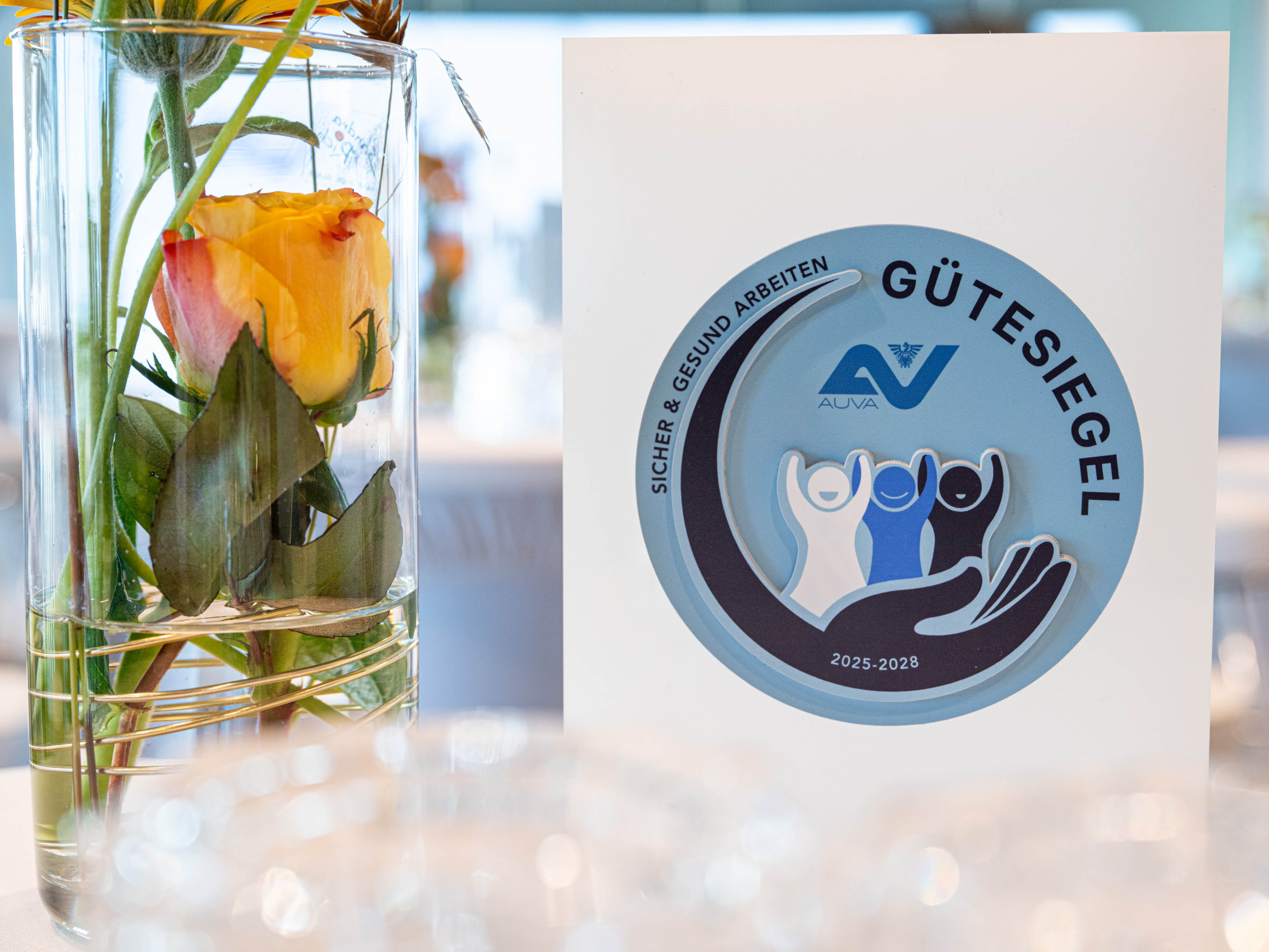 Trophäe mit AUVA-Gütesiegel-Aufdruck neben einer Blumenvase