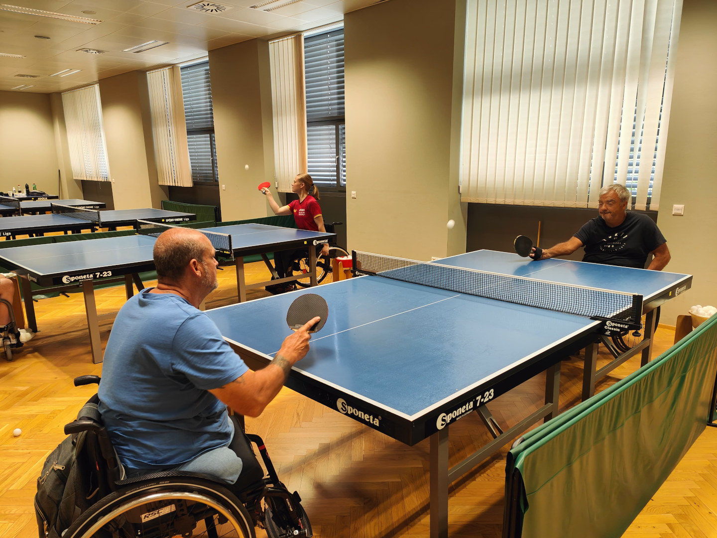 Rollstuhltischtennis: Im Bild sind eine Spielerin und zwei Spieler