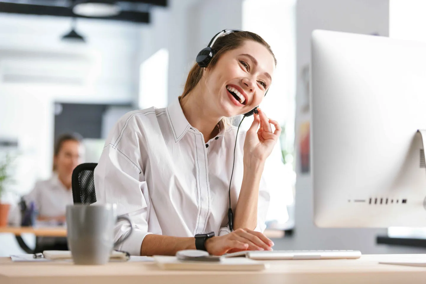 Adobestock 233378937 1440©Drobot Dean Web Lächelnde Frau mit Headset sitzt vor einem Bildschirm