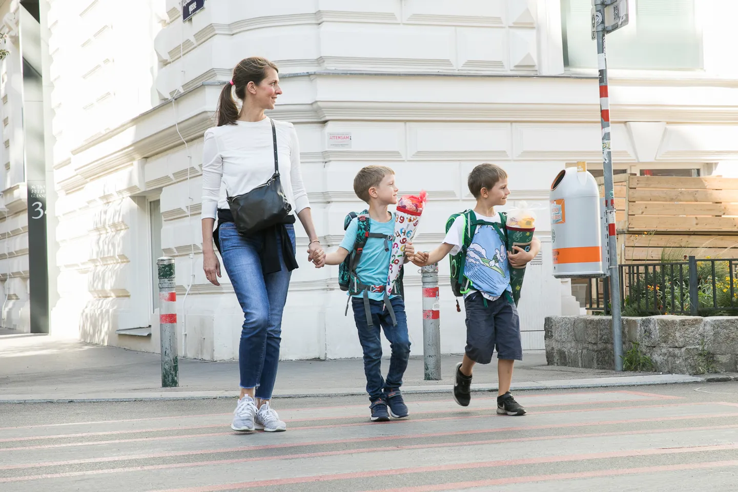 Schulkinder mit erwachsener Begleitperson beim Überqueren einer Straße Schulkinder mit erwachsener Begleitperson beim Überqueren einer Straße