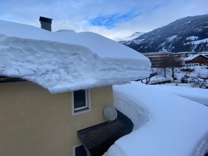 Ein Haus in den Bergen mit Schnee am Dach