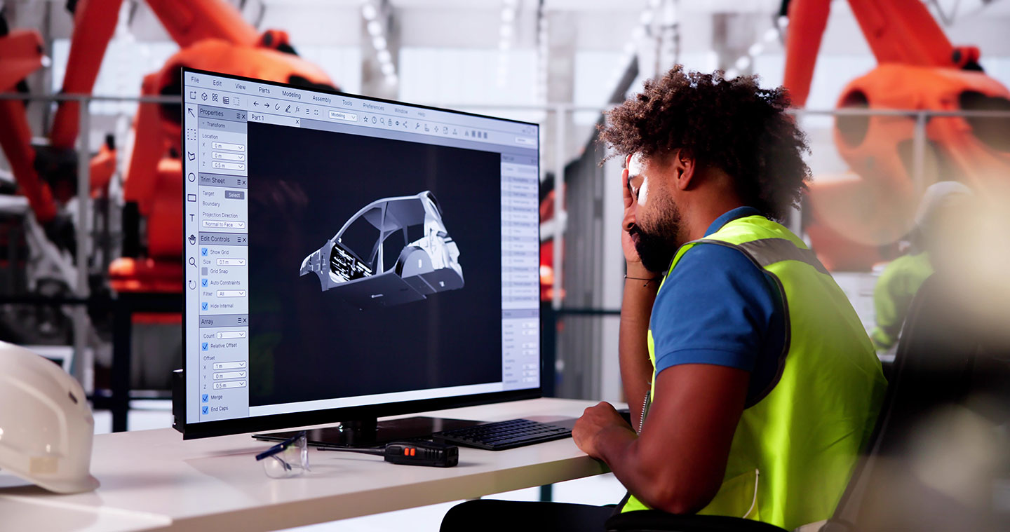 Ein müde wirkender Mann sitzt an einem Schreibstisch mit Bildschirm und stützt den Kopf in die rechte Hand.