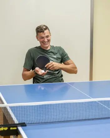 Ein lächelnder Tischtennisspieler bei der Angabe