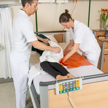 M105 Transfers Im Bett Nach Oben Rutschen 2 Pflegepersonen Zwei Pflegefachkräfte helfen Patient dabei im Bett nach oben zu rutschen
