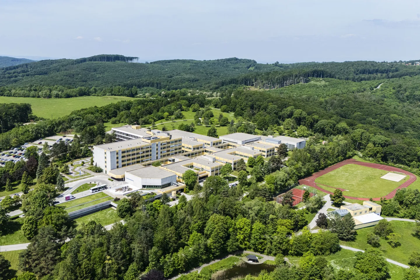 Luftaufnahme des AUVA-Rehabilitationszentrums Weißer Hof mit Sportplatzanlage in Naturlandschaft Luftaufnahme des AUVA-Rehabilitationszentrums Weißer Hof mit Sportplatzanlage - eingebettet in Naturlandschaft mit zahlreichen Bäumen