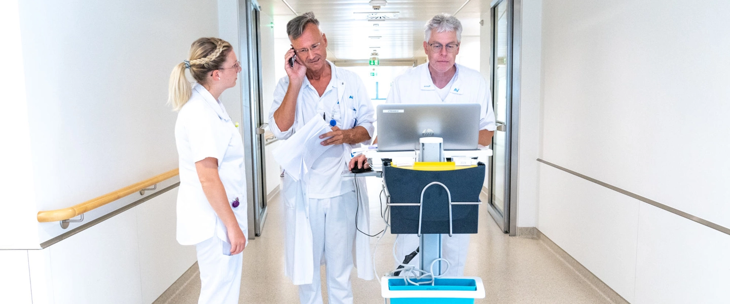 AUVA-Gesundheitseinrichtungen - 230909 (c) VDR 001 (1) Drei Personen am Gang einer AUVA-Gesundheitseinrichtung auf dem Weg zur Visite