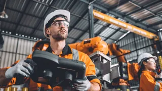 Mann arbeitet mit Roboter.