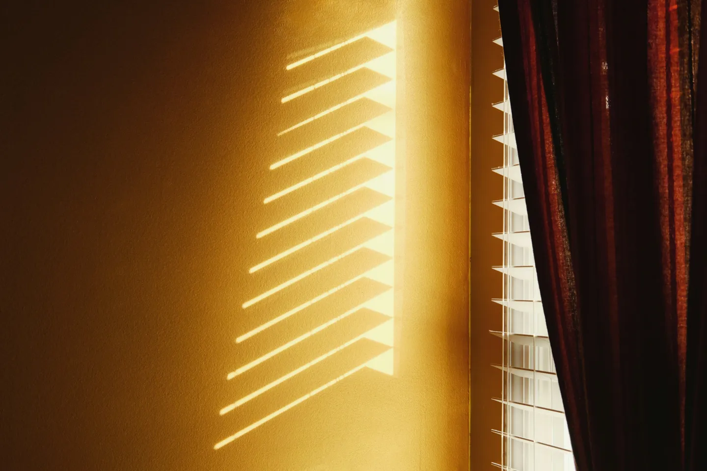 Beschattung Fenster Credit Ariel Auf Unsplash Blick auf Fenster mit halb geschlossener Jalousie und leicht geöffnetem Vorhang