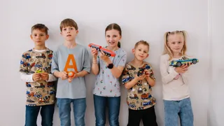 Verkehrsgeräuschequiz Fünf Kinder stehen nebeneinander und halten verschiedene Spielzeug-Verkehrsmittel in ihren Händen.