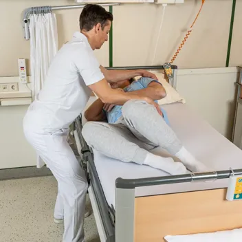 M105 Vom Querbett Sitz Zur Rueckenlage Pflegefachkraft hilft Patient vom Querbett-Sitz in die Rückenlage zu gelangen