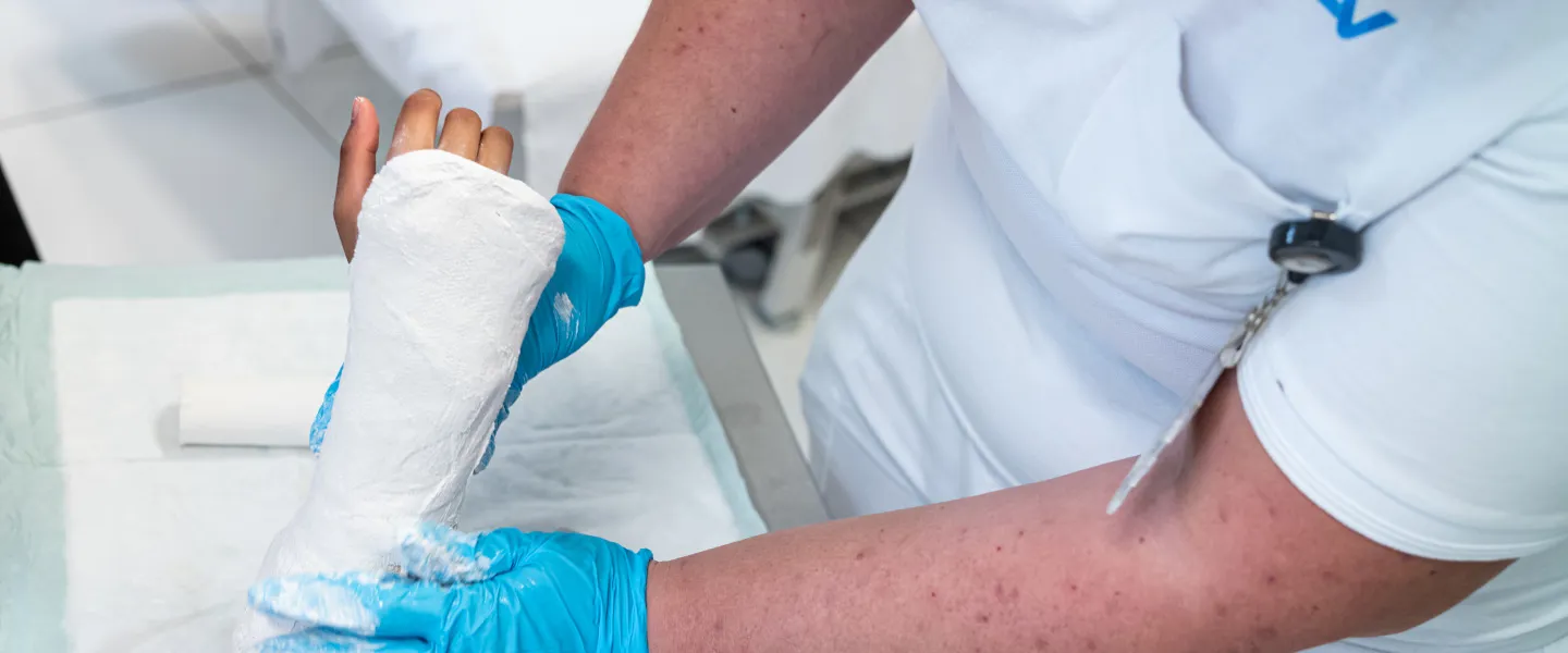 Einer Patientin / Einem Patienten wird im durch einen Arzt im Bereich es Unterarms ein Gipsverband angelegt