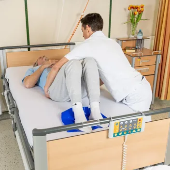 M105 Im Bett Zur Seite Rutschen Pflegefachkraft hilft Patient dabei im Bett zur Seite zu rutschen