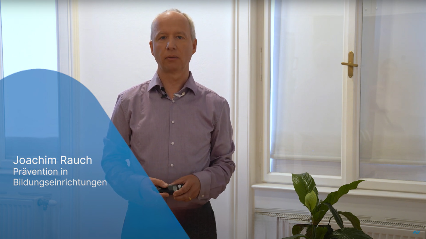 Ein Mann steht vor einem Fenster und spricht in die Kamera