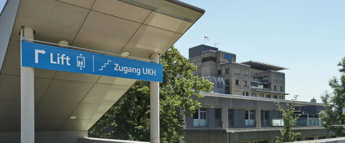 Lift- und Stiegenzugang zum UKH Graz im Vordergrund des Bildes, Hauptgebäude des UKH im Hintergrund